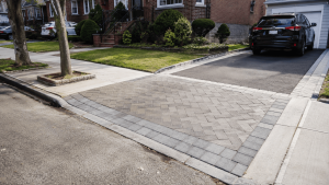 Driveway apron pavers in NYC installed between the street and a residential driveway, with a clean border, curb cut, and parked SUV.