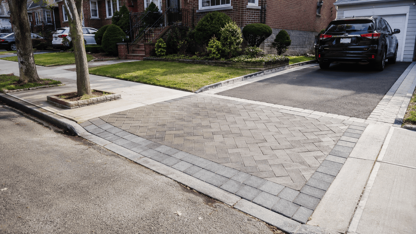 Driveway apron pavers in NYC installed between the street and a residential driveway, with a clean border, curb cut, and parked SUV.
