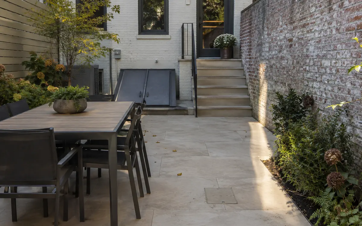 Large-format porcelain paver patio in a landscaped urban townhouse backyard