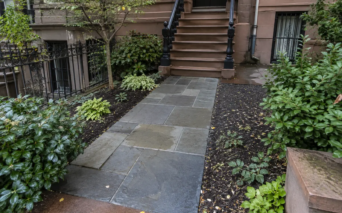 Finished stone paver walkway with landscaped edges at a residential property