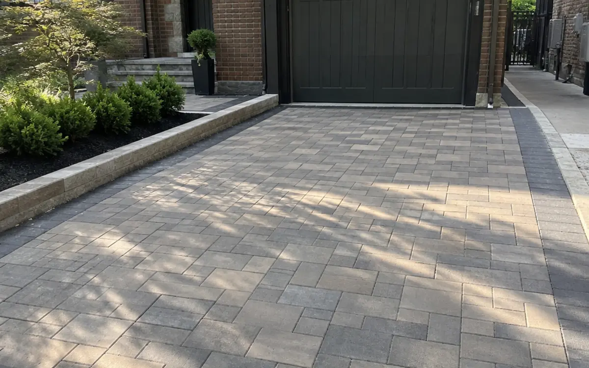 Concrete paver driveway with clean pattern and landscaped residential entrance