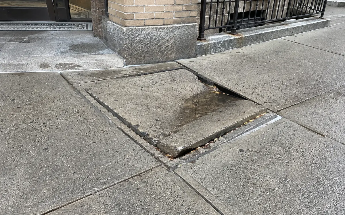 Multiple cracked and uneven NYC sidewalk flags requiring concrete repair or replacement